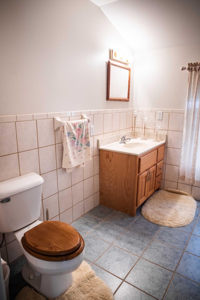 bathroom featuring vanity, tile walls, tile flooring, vaulted ceiling, and toilet