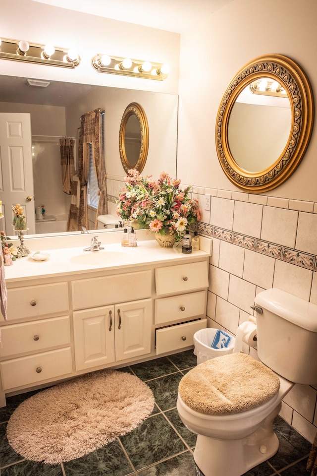 bathroom with vanity with extensive cabinet space, toilet, tile floors, and tile walls