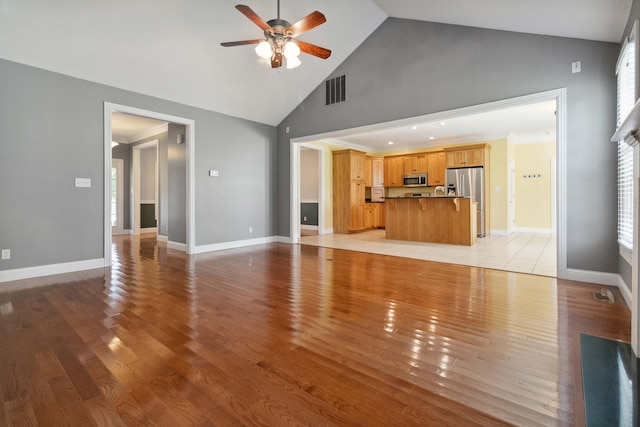 unfurnished living room featuring light hardwood / wood-style floors, high vaulted ceiling, a wealth of natural light, and ceiling fan