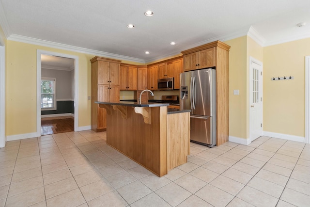 kitchen with stainless steel appliances, a center island with sink, ornamental molding, a breakfast bar, and light tile patterned floors