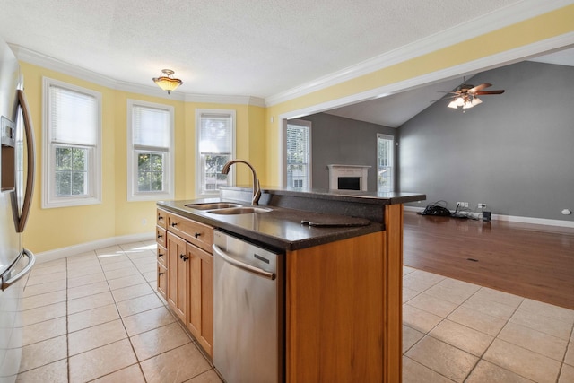 kitchen with appliances with stainless steel finishes, sink, a textured ceiling, light hardwood / wood-style floors, and a kitchen island with sink