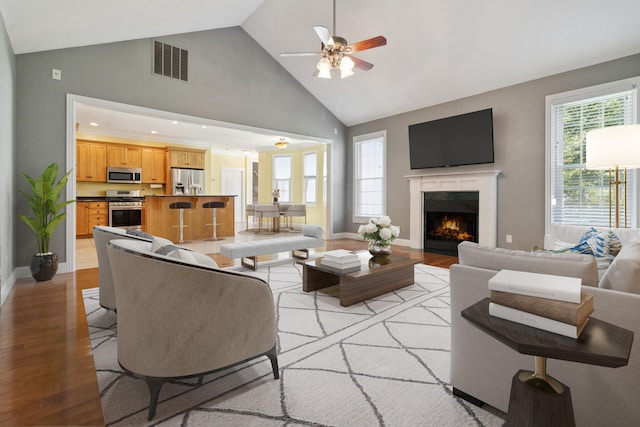 living room featuring ceiling fan, high vaulted ceiling, and light hardwood / wood-style flooring