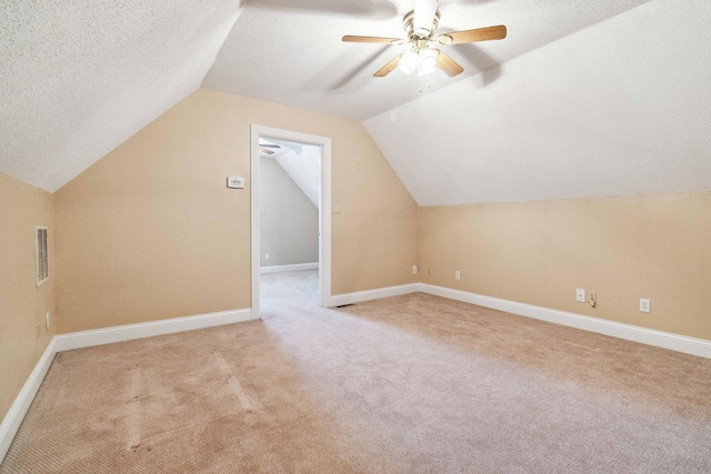 bonus room with light carpet, lofted ceiling, a textured ceiling, and ceiling fan