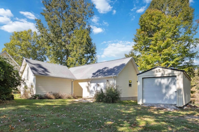 rear view of house featuring an outdoor structure, a lawn, and a garage