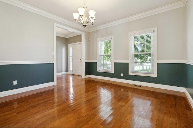 spare room featuring ornamental molding, a chandelier, and wood-type flooring