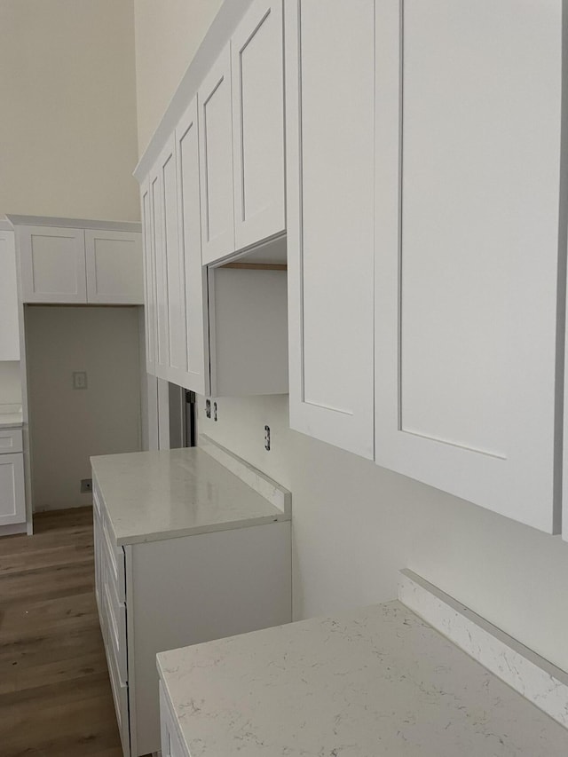 kitchen featuring light stone counters, dark wood-style flooring, and white cabinetry