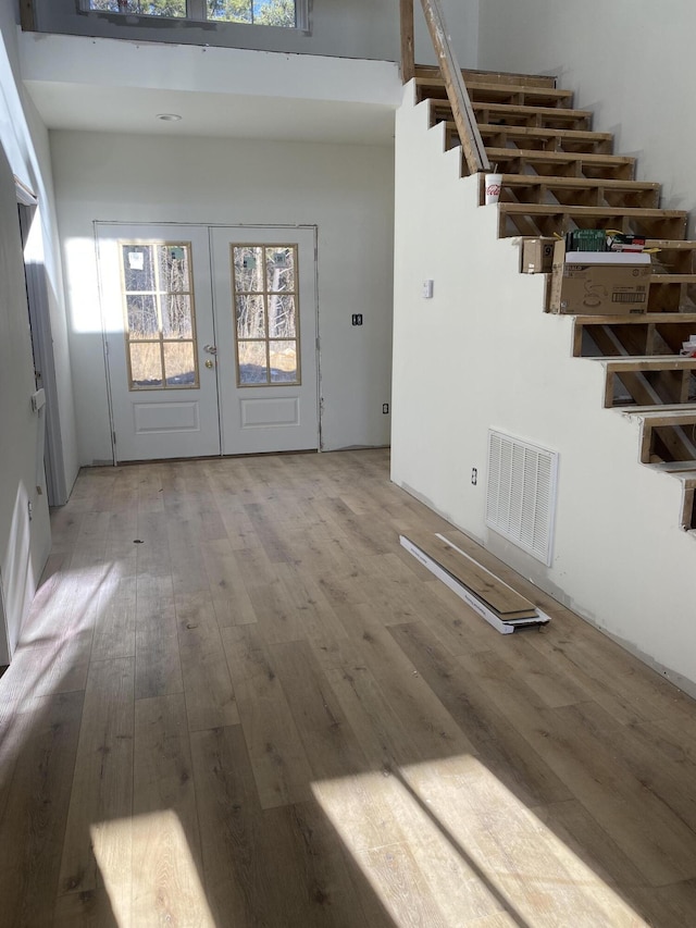 entryway featuring hardwood / wood-style flooring, plenty of natural light, a high ceiling, and french doors