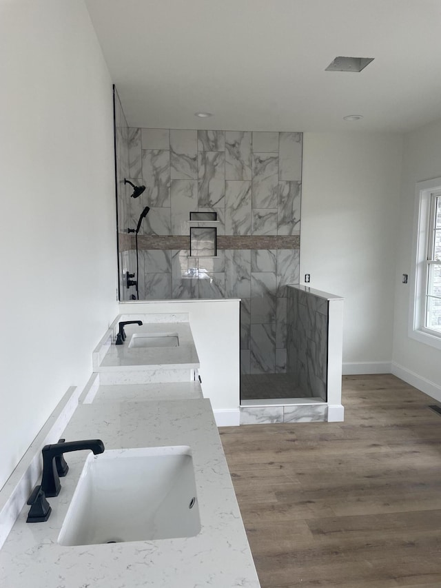 bathroom featuring a sink, a marble finish shower, and wood finished floors