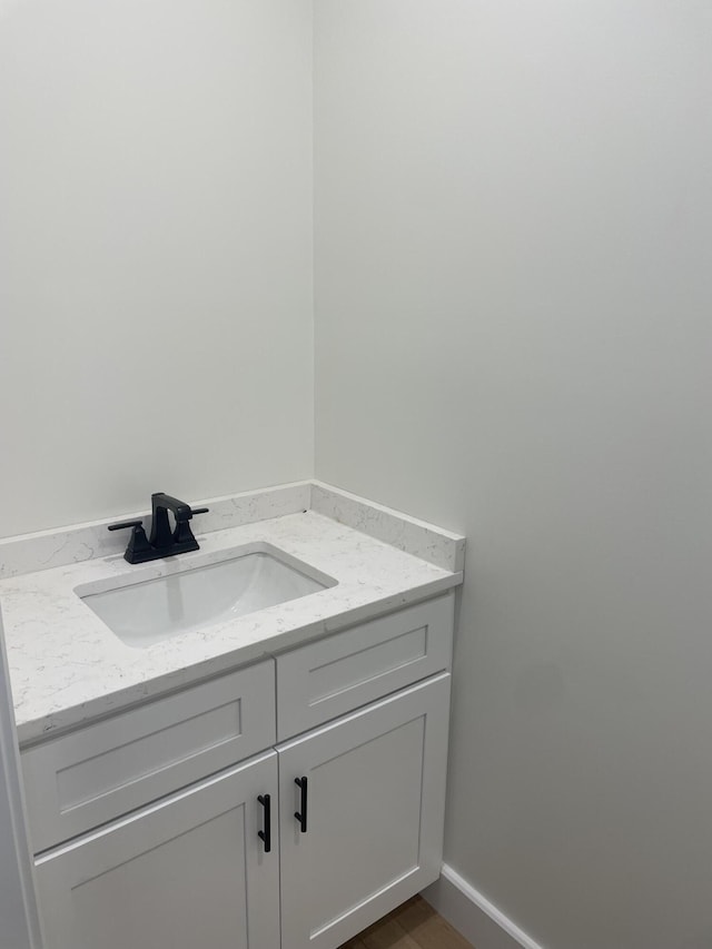 bathroom featuring vanity, baseboards, and wood finished floors