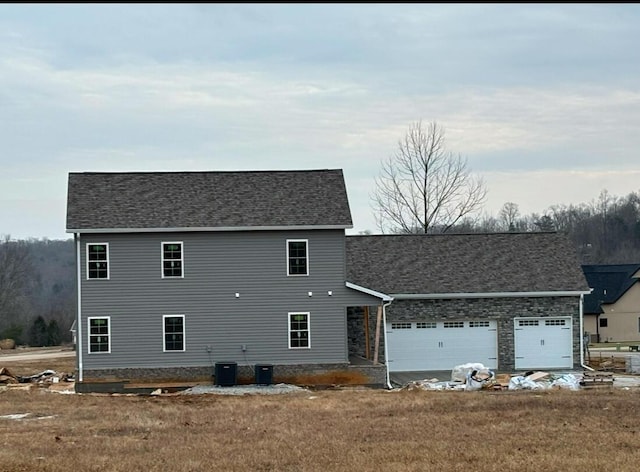 view of front of house with a garage, central AC unit, and a front yard