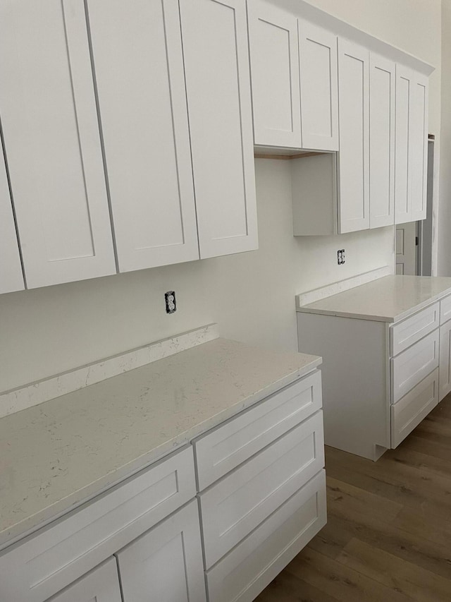 kitchen with light stone countertops, dark hardwood / wood-style floors, and white cabinets