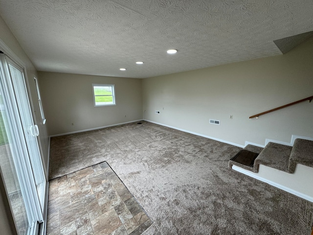 carpeted spare room with a textured ceiling