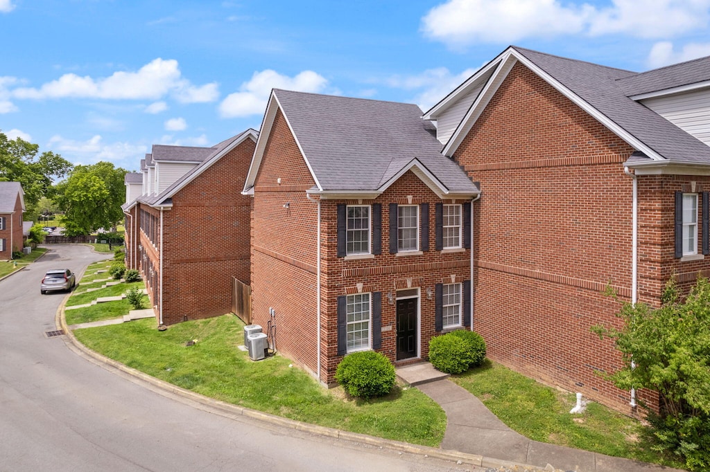 view of front facade featuring a front lawn and central air condition unit