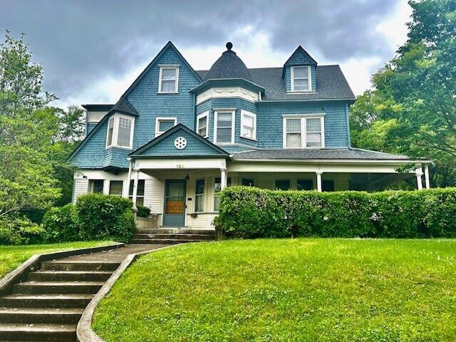 victorian-style house featuring a porch and a front yard