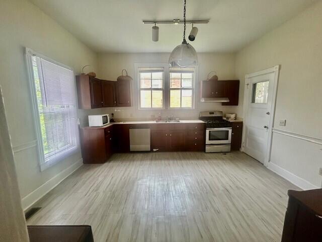 kitchen featuring hanging light fixtures, dishwasher, stove, extractor fan, and light wood-type flooring