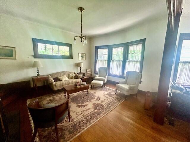 living area featuring plenty of natural light, hardwood / wood-style floors, and an inviting chandelier