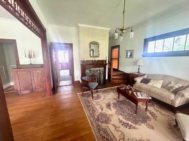 living room with a chandelier, plenty of natural light, wood-type flooring, and crown molding