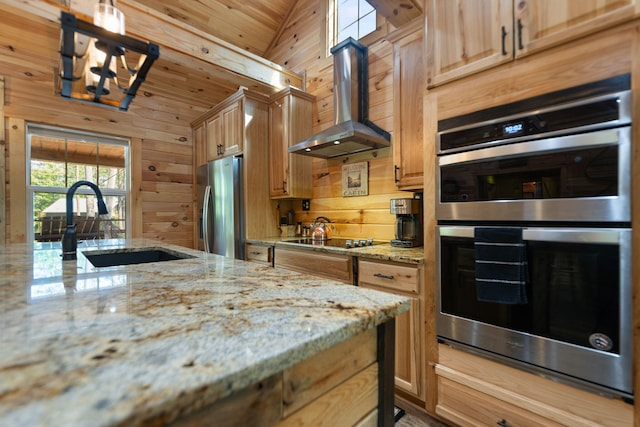 kitchen featuring stainless steel appliances, vaulted ceiling, wall chimney range hood, and light stone countertops