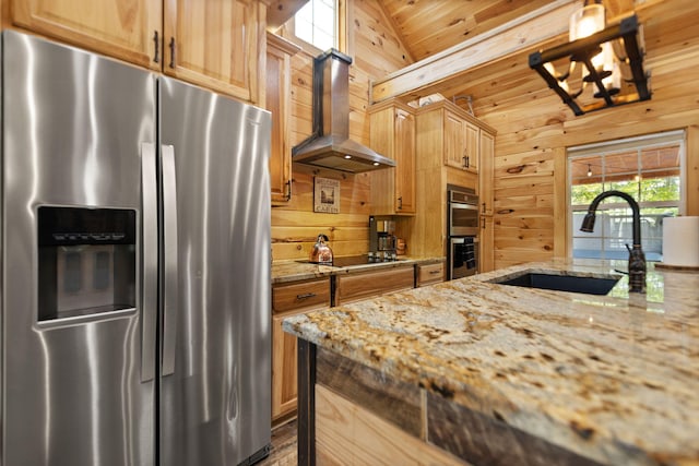 kitchen featuring appliances with stainless steel finishes, light stone counters, vaulted ceiling, and wall chimney exhaust hood