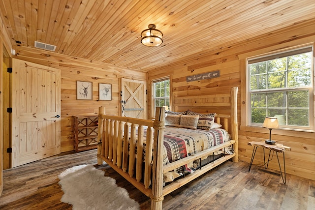 bedroom with multiple windows, wood walls, and hardwood / wood-style floors