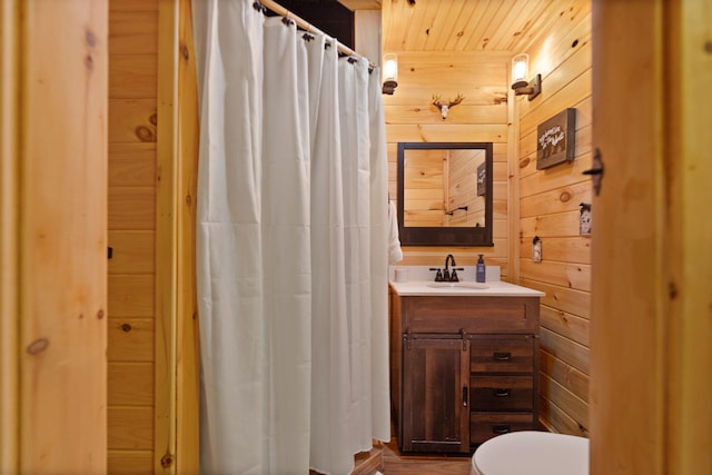 bathroom with toilet, wood walls, and oversized vanity