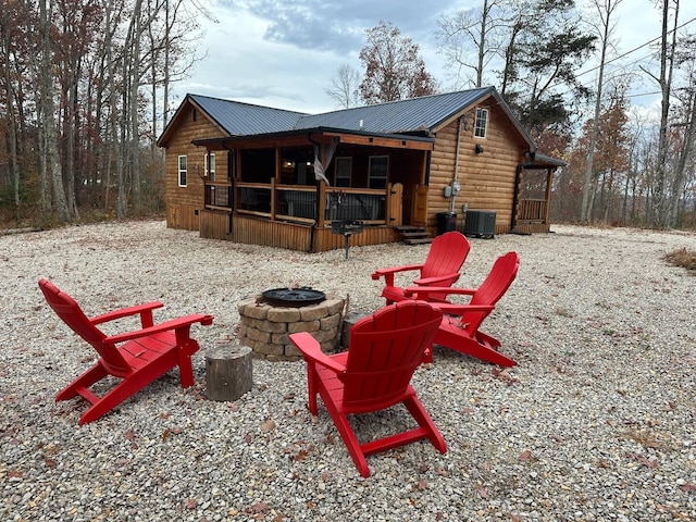 rear view of property with central air condition unit and a fire pit