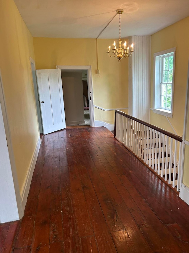 empty room featuring dark hardwood / wood-style flooring and a chandelier