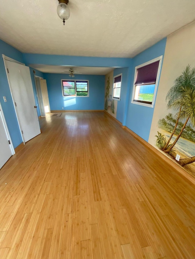 unfurnished living room featuring plenty of natural light, ceiling fan, and light wood-type flooring