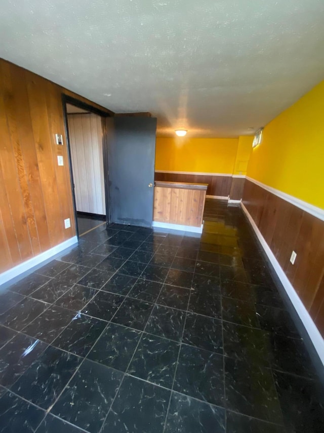 tiled empty room with wood walls and a textured ceiling