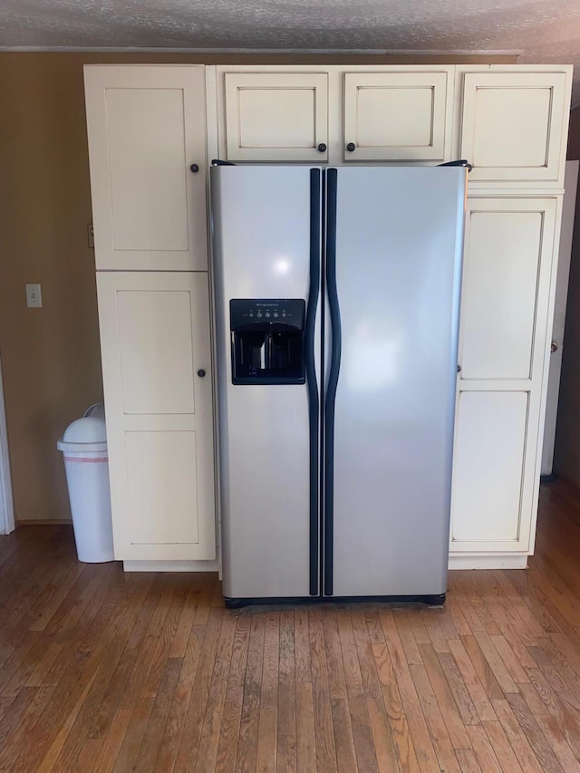 kitchen with hardwood / wood-style flooring, white cabinetry, and stainless steel fridge