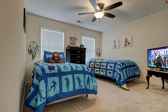 carpeted bedroom featuring ceiling fan and a textured ceiling