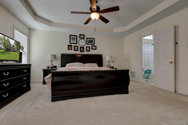 carpeted bedroom with ceiling fan, a raised ceiling, and a textured ceiling