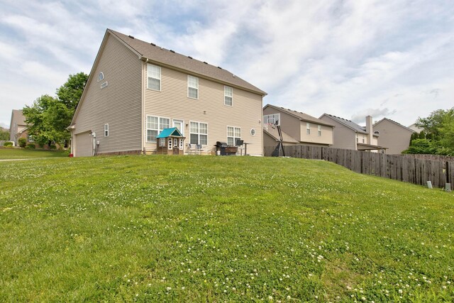 rear view of property featuring a garage and a yard