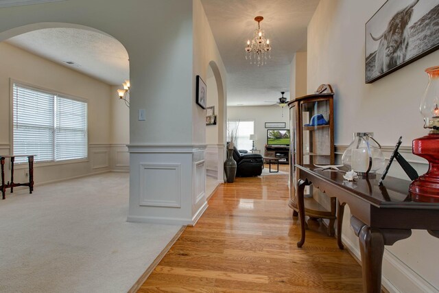 hall with a textured ceiling, light hardwood / wood-style flooring, and a notable chandelier