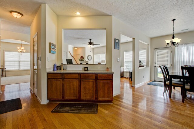 kitchen featuring plenty of natural light, ceiling fan with notable chandelier, and light wood-type flooring