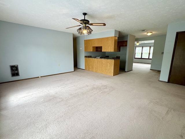 unfurnished living room featuring light carpet, ceiling fan, and a textured ceiling