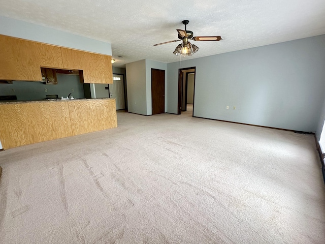 interior space featuring light carpet, ceiling fan, and a textured ceiling