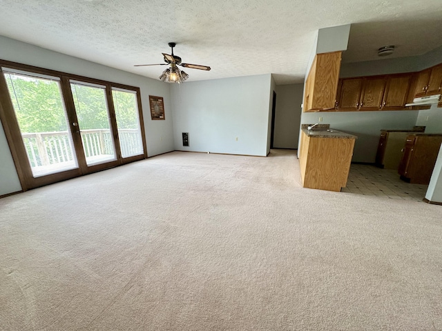 unfurnished living room with sink, ceiling fan, and light carpet