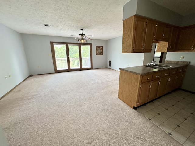 kitchen featuring a textured ceiling, light carpet, ceiling fan, and sink