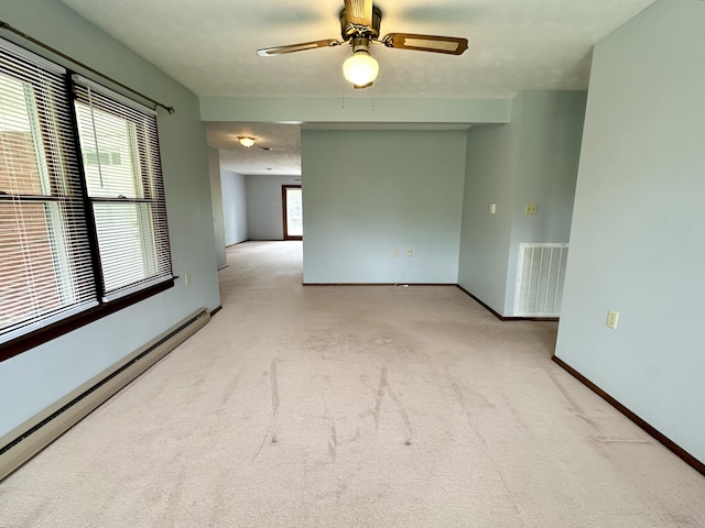 carpeted spare room featuring a baseboard radiator and ceiling fan