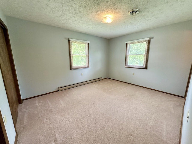 spare room with baseboard heating, carpet floors, and a textured ceiling