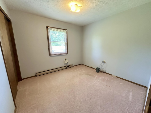 spare room featuring a baseboard radiator, carpet floors, and a textured ceiling