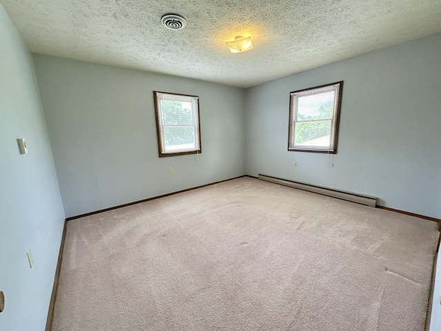 spare room featuring a baseboard radiator, carpet, plenty of natural light, and a textured ceiling