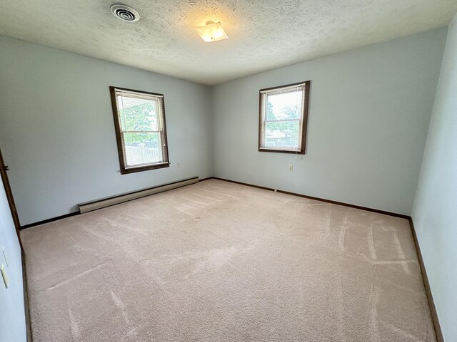 carpeted spare room with baseboard heating and a textured ceiling