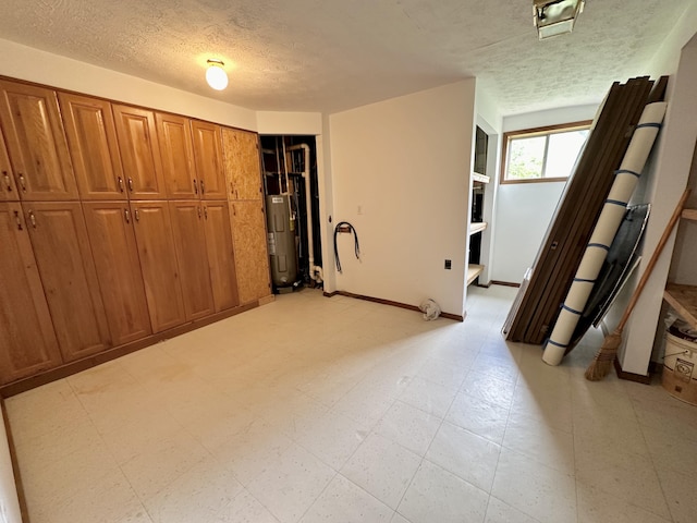 unfurnished bedroom with a textured ceiling, a closet, light tile floors, and electric water heater