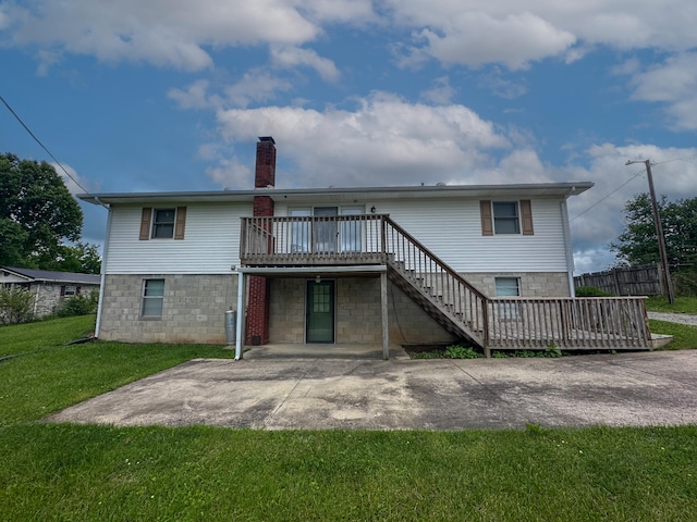 rear view of house featuring a patio area, a wooden deck, and a lawn