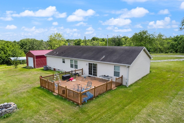 rear view of house with a deck, central AC unit, an outbuilding, a garage, and a lawn