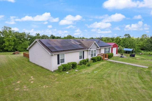 view of front of property featuring solar panels, a front yard, an outbuilding, and a garage