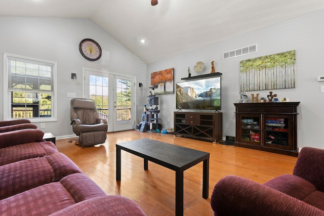 living room featuring high vaulted ceiling, french doors, and hardwood / wood-style floors