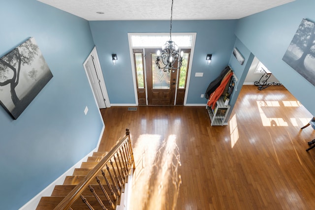 entryway featuring an inviting chandelier, a textured ceiling, and wood-type flooring